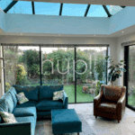 hup conservatory, A bright sunroom with a uPVC glass roof, large sliding glass doors and lush green plants—looking out onto a garden in West Sussex.