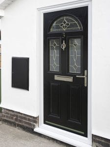 A stylish black composite front door with glass panels and decorative leaded designs, featuring a silver handle, letterbox, and knocker. Set in a white wall, it's a chic entrance typical of West Sussex homes.